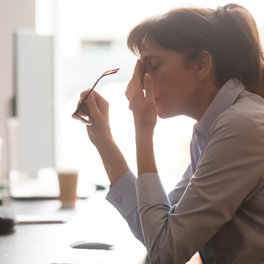 woman holds her glasses and touches her head-small